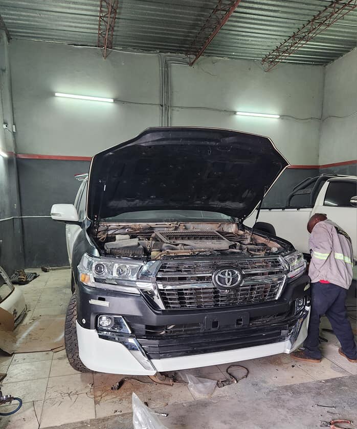 Land Cruiser face-lift kit installation and paint preparation, mechanic alongside