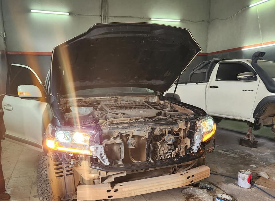 Headlamp diagnostics and daytime-running-light testing on a Toyota Land Cruiser in the AGM bay